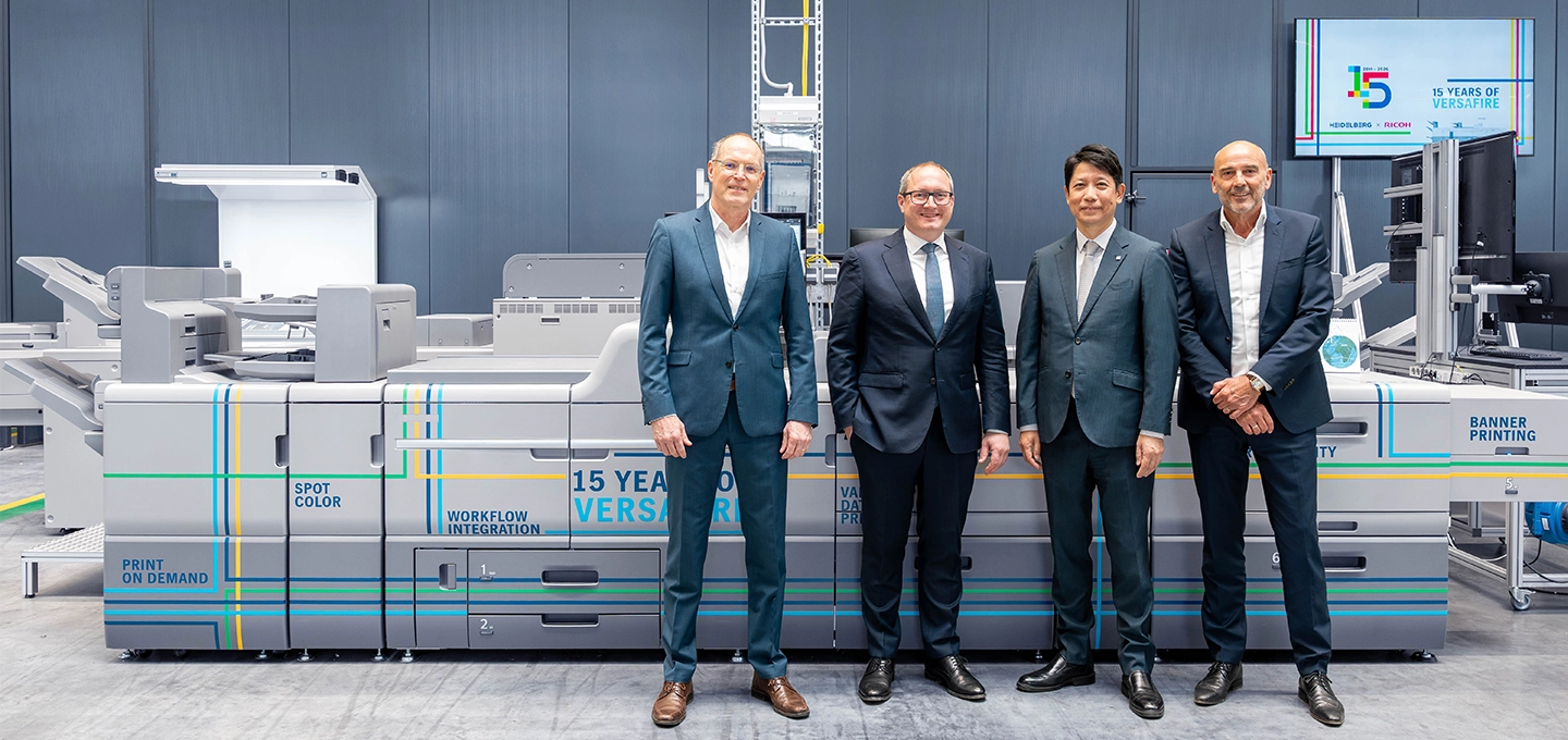 HEIDELBERG and RICOH leaders celebrating 15 years of Versafire digital printing systems at a production facility.